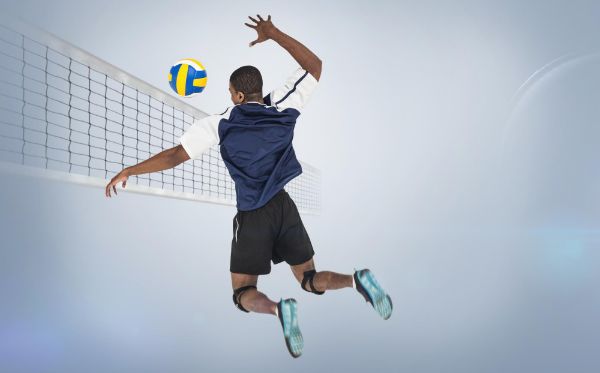 sportsman hitting volleyball against a grey background